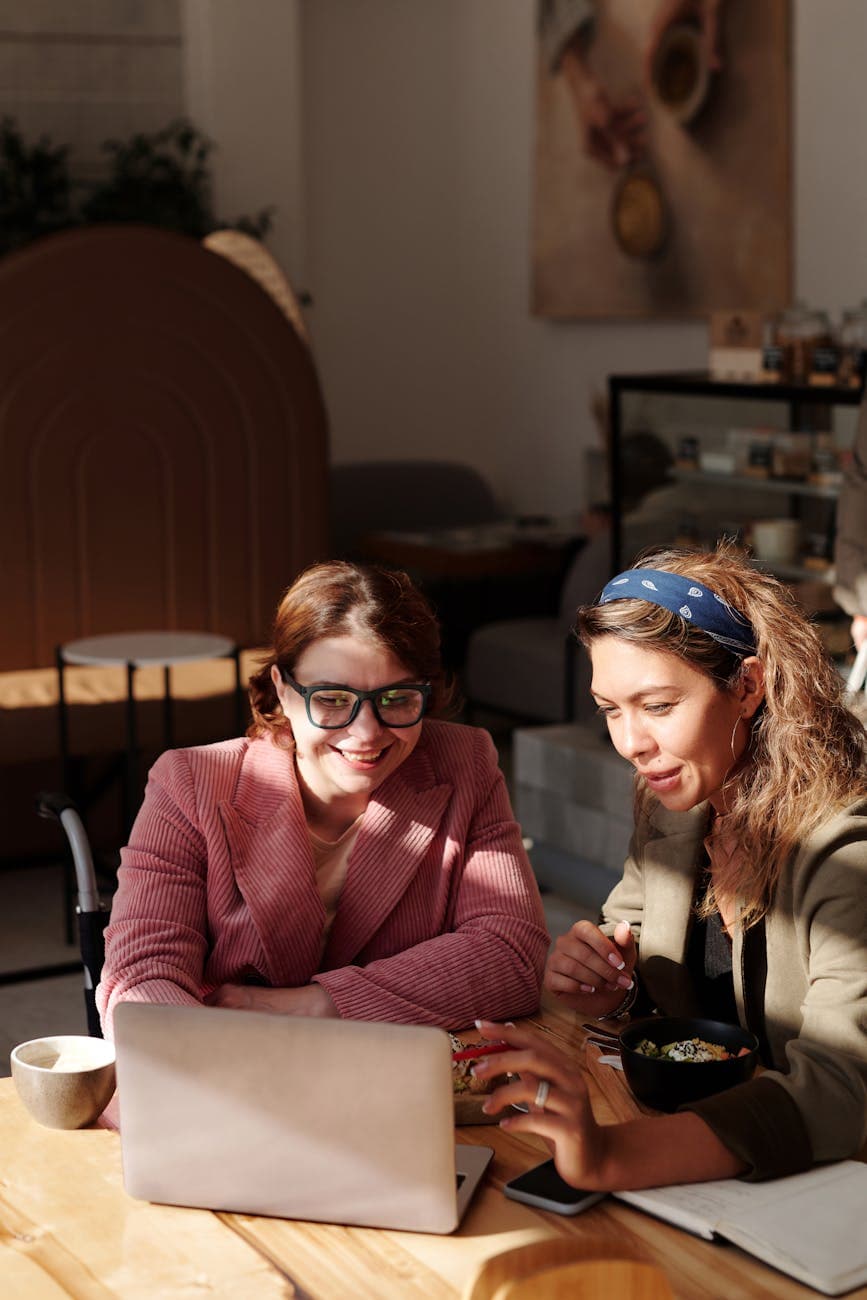 Two colleagues collaborating over a laptop in a bright workspace