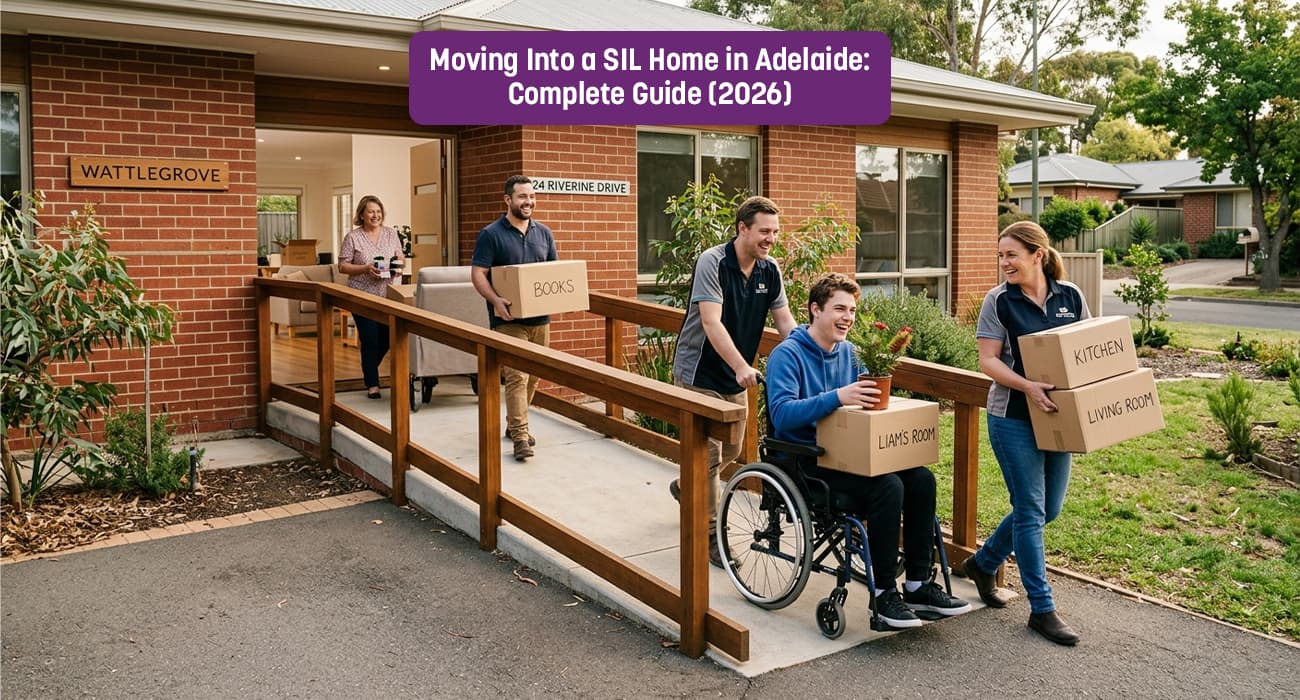 A group of cheerful support workers and a young man in a wheelchair moving boxes into a modern brick SIL home in Adelaide named 'Wattlegrove'. The scene shows a wooden accessibility ramp and boxes labeled 'Liam's Room' and 'Kitchen', representing a smooth transition into Supported Independent Living with Nurse Aid Australia.
